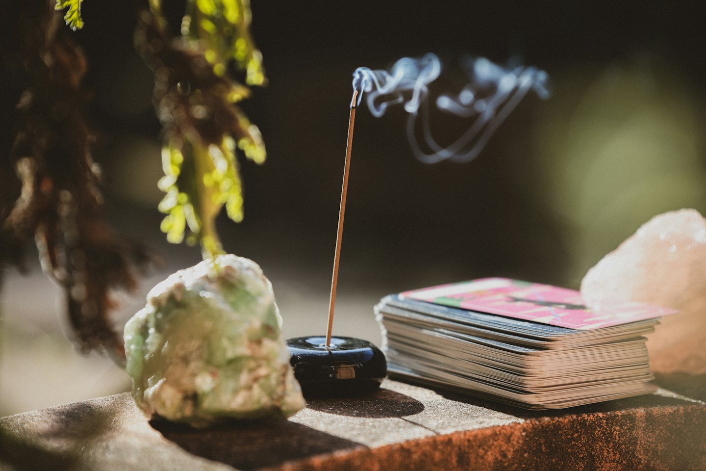 Incense smoke drifts between a crystal and tarot cards.